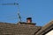 Newly fitted chimney cowl fitted to a chimney pot seen with a TV antenna.