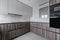 Newly installed kitchen in contemporary design with root wood cabinets, glossy black appliances and gray tile floors