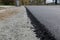 Newly laid black bitumen asphalt with a high edge to the gravel