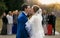 Newly married couple kissing in front of happy guests at park