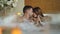 Newly married couple is relaxing in jacuzzi kissing, touching hands, talking and laughing. Romantic relationship