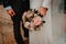 A newly married couple show their bouquet of flowers out of church