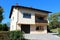 Newly renovated suburban family house with front balcony and stone tiles driveway surrounded with hedge and trees