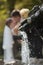 Newly wedded kissing behind fountain