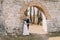 Newlywed couple pose at old ruined gate of ancient baroque castle wall