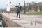 Newlywed couple walking on embarkment, two stem glasses with champagne standing on granite