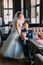 Newlywed enloved couple. Beautiful bride in white dress standing near handsome groom blue suite posing indoors, luxury