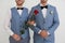 Newlywed gay couple with rose near white wall
