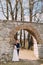 Newlywed pair pose at old ruined gate of ancient baroque castle wall