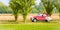 A newlywed unidentifiable couple is driving a retro car on a country road for their honeymoon