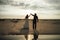 Newlyweds dancing on sandy beach. Bride and groom in evening back-light. Barefoot dance, mirror reflection. Wedding day