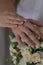 Newlyweds demonstrate wedding rings on the fingers, putting a hand on the hand above the bouquet