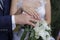 Newlyweds demonstrate wedding rings on hands over a bouquet of white lilies