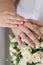 Newlyweds demonstrate wedding rings, holding hands on a bouquet of white roses