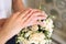 Newlyweds demonstrate wedding rings over a bouquet of roses