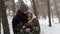 Newlyweds groom and bride hug kiss and warm each other in snowy pine forest during snowfall in slow motion. . Young