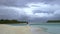 Newlyweds hold hands on a gorgeous white sand beach and turquoise water. In the background is a beautiful sky. Wedding on a tropic