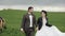 Newlyweds hold hands on a walk in the countryside next to a grazing horse. Close-up. Slow-motion. The camera moves from