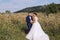 Newlyweds hugging in a meadow amongst tall grass and flowers