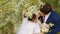 Newlyweds kiss on the branches of a flowering tree