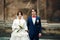 Newlyweds look seriously standing behind an old cathedral