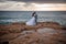The newlyweds pose in wedding clothes on the rocks by the sea. Beautiful young couple tenderly embracing. Newlyweds