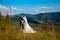 Newlyweds smile and hug each other among the meadow on top of the mountain. Wedding walk in the woods in the mountains, the gentle