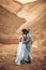 Newlyweds stand and hug in canyon against background of river.