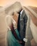 Newlyweds stand under bridal veil and hold hands in canyon at sunset.