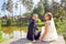 newlyweds turning back and looking at camera while sitting on wooden pier near lake at sunny summer day