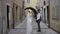 Newlyweds walking around the city with bright houses. Action. A young couple walking hand in hand along narrow roads