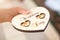 Newlyweds wedding rings on a wooden heart-shaped stand in the church