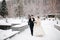 Newlyweds in witer park are walking around. Handsome groom and beautiful bride surrounded by snow. Winter wedding