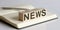 The NEWS sign on wooden block on notebook background