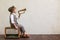 Newsboy shouting against grunge wall background. Boy selling newspaper