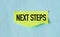 Next Steps text on yellow stickers attached on blue background