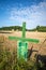 Next to  grain field there is a green cross as a symbol of protest of the farmers