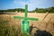 Next to  grain field there is a green cross as a symbol of protest of the farmers