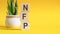 nfp concept with wooden blocks on table, yellow background