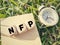 NFP on wooden cubes. Abbreviation for Natural Family Planning or stands for NonFarm Payrolls. Green background.