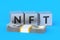 NFT inscription on cubes near stack of money. Non-fungible token. Blockchain technology concept