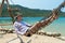 NHA TRANG, VIETNAM - APRIL 19, 2019: A man in a hat lies in a hammock on a sandy beach in tropics