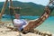 NHA TRANG, VIETNAM - APRIL 19, 2019: A man in hat lies in a hammock on a sandy beach in tropics