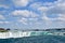 The Niagara River becomes Niagara Falls under a beautiful partly cloudy sky