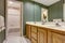 Nice bathroom in green tones with cabinets, double sink and tile floor.
