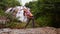 Nice blond girl bends body in yoga pose by waterfall