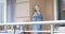 A nice blond girl is standing on the balcony and sending an air kiss.