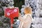 Nice blonde curly girl with letter near the Santa`s mailbox