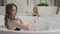Nice blonde girl with curly hair in a black swimsuit with blue eyes enjoys relax in warm water in a brand new jacuzzi