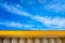 Nice blue sky with clouds, over a yellow canopy of a factory